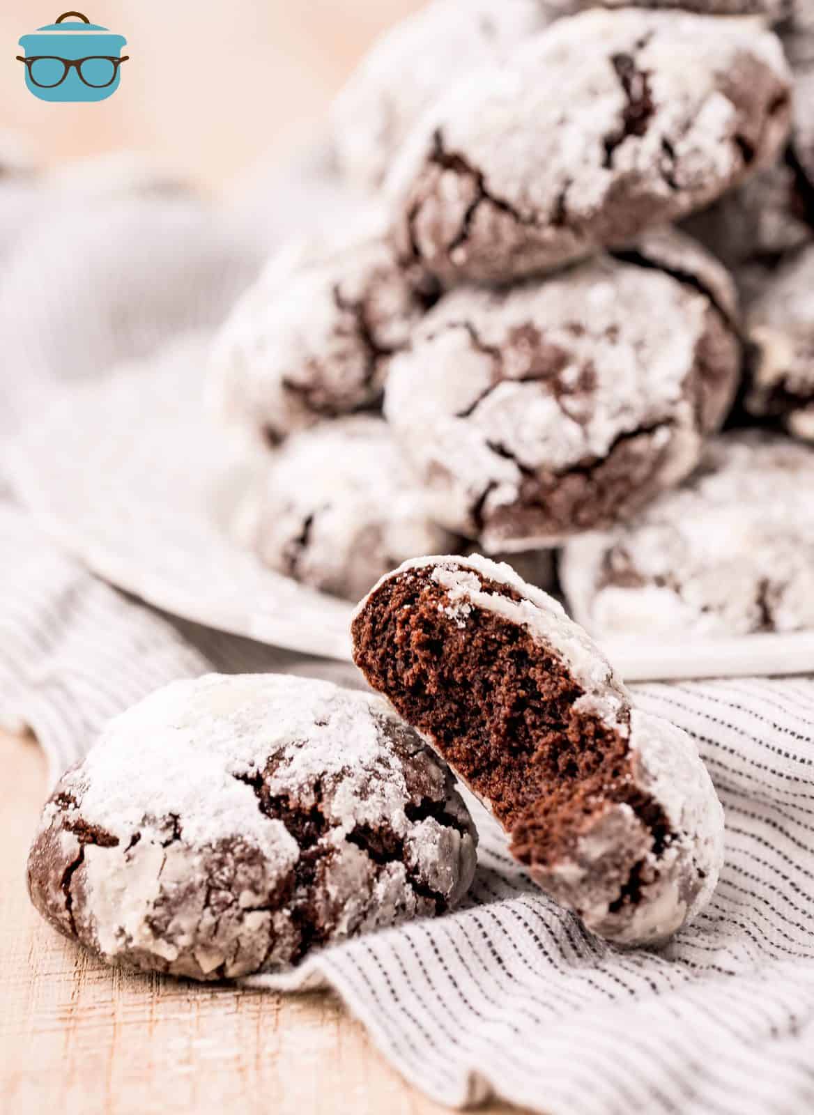 Chocolate Crinkle Cookies on linen with one leaning up against another with bite taken out.
