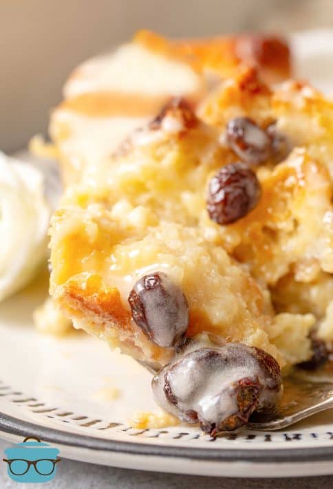 Close up of slice of bread pudding with sauce and raisins.