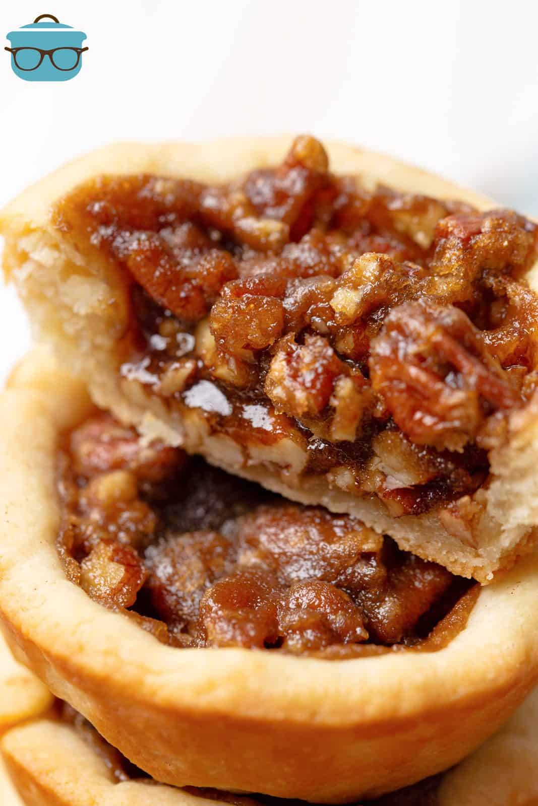 Close up of stacked Pecan Tassies with one cut in half showing filling.