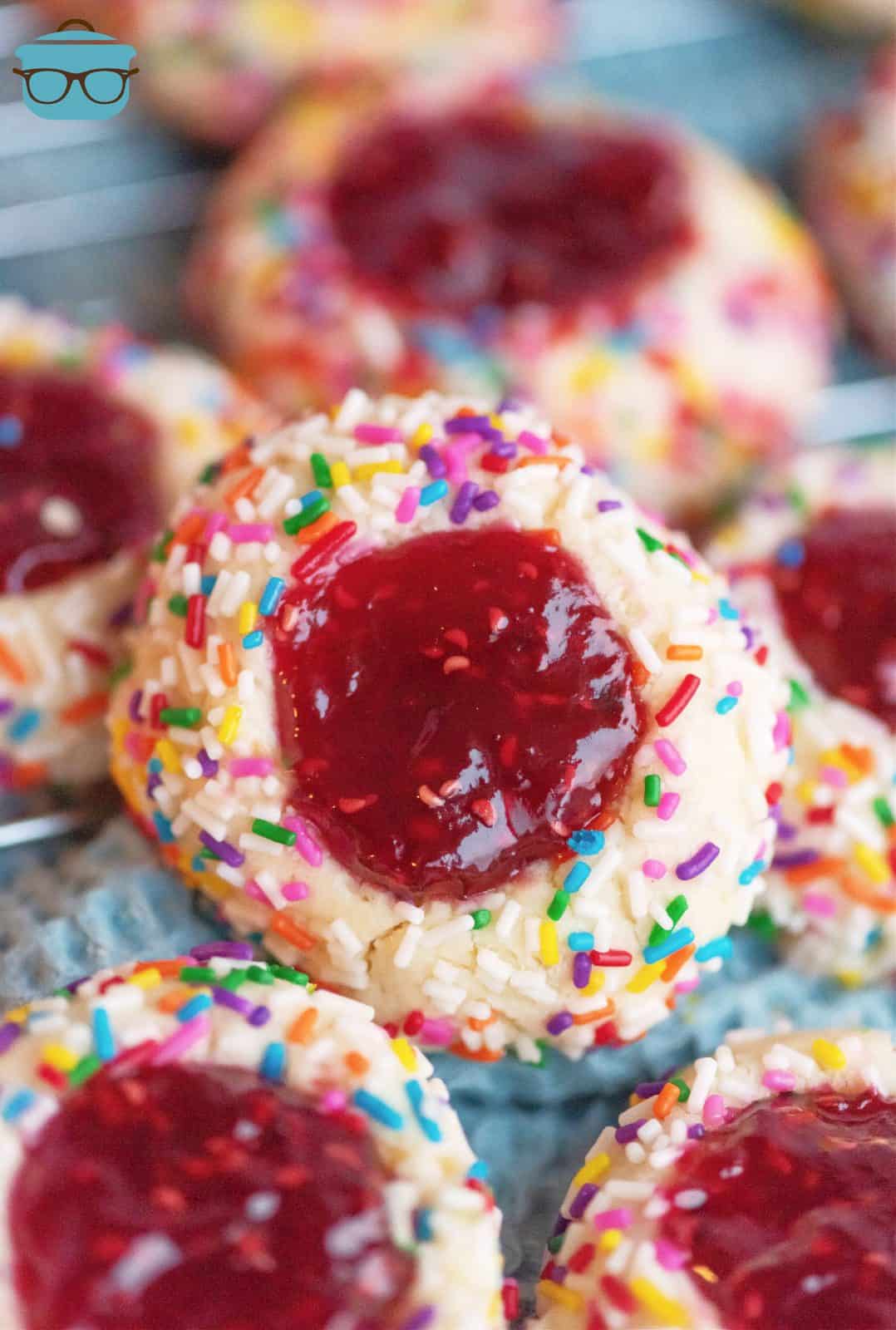 Raspberry Thumbprint Cookies on board with one stacked up showing filling.