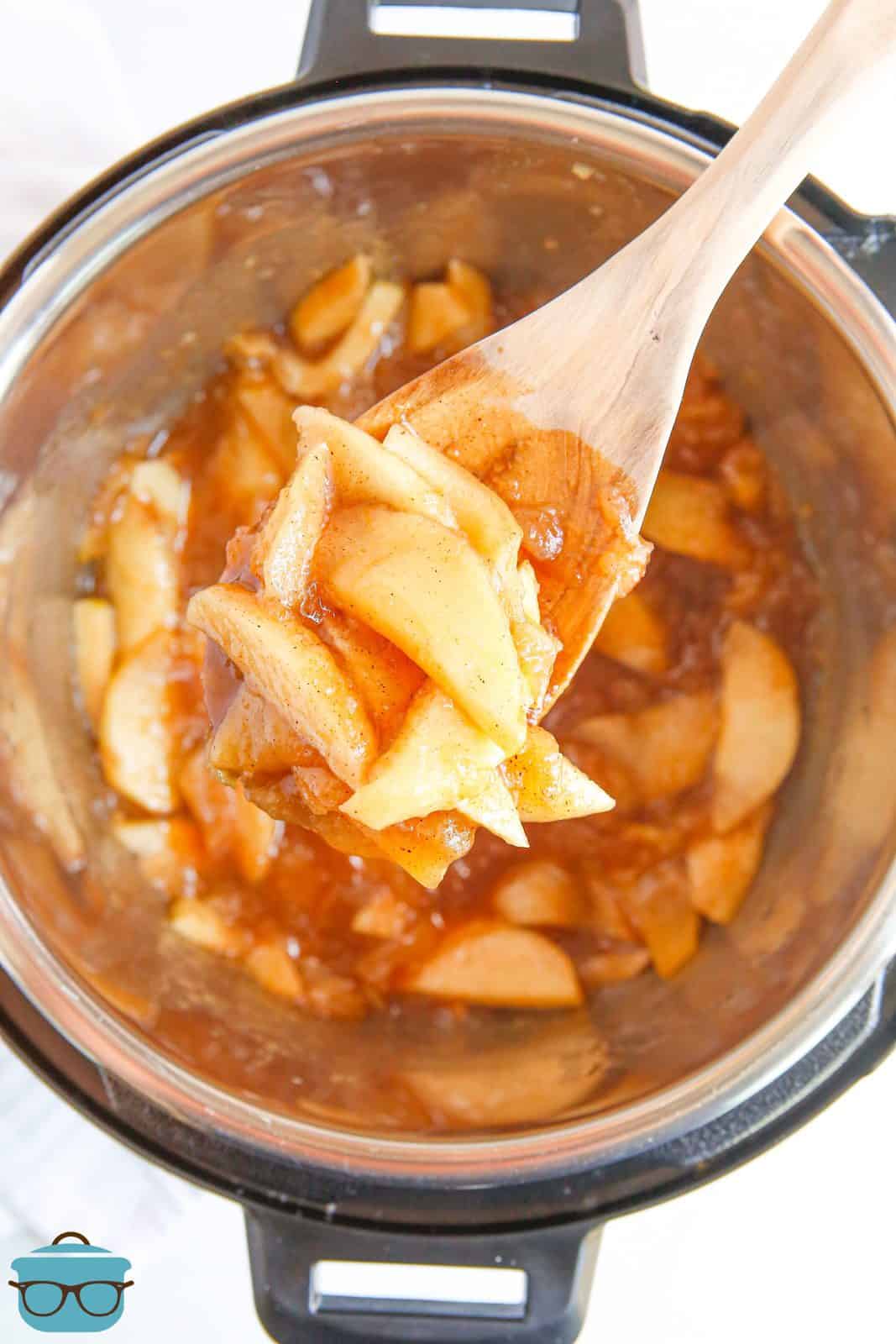 Wooden spoon lifting up Fried Apples out of instant pot.