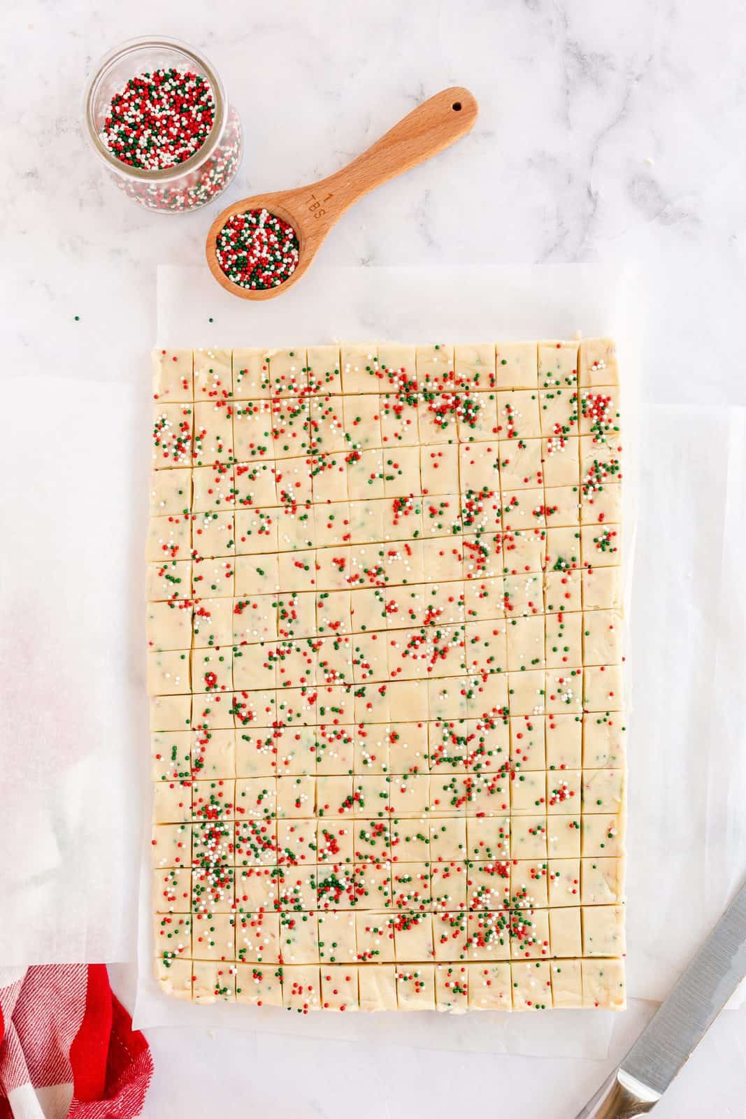 Shortbread dough cut into small squares on parchment paper.