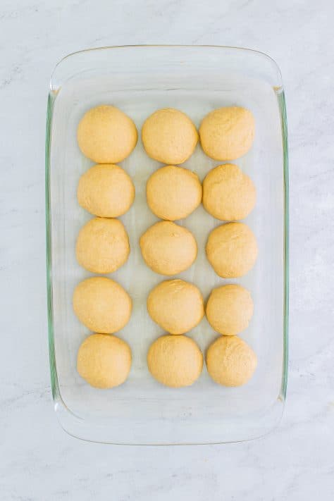 Dough balls added to buttered baking pan.