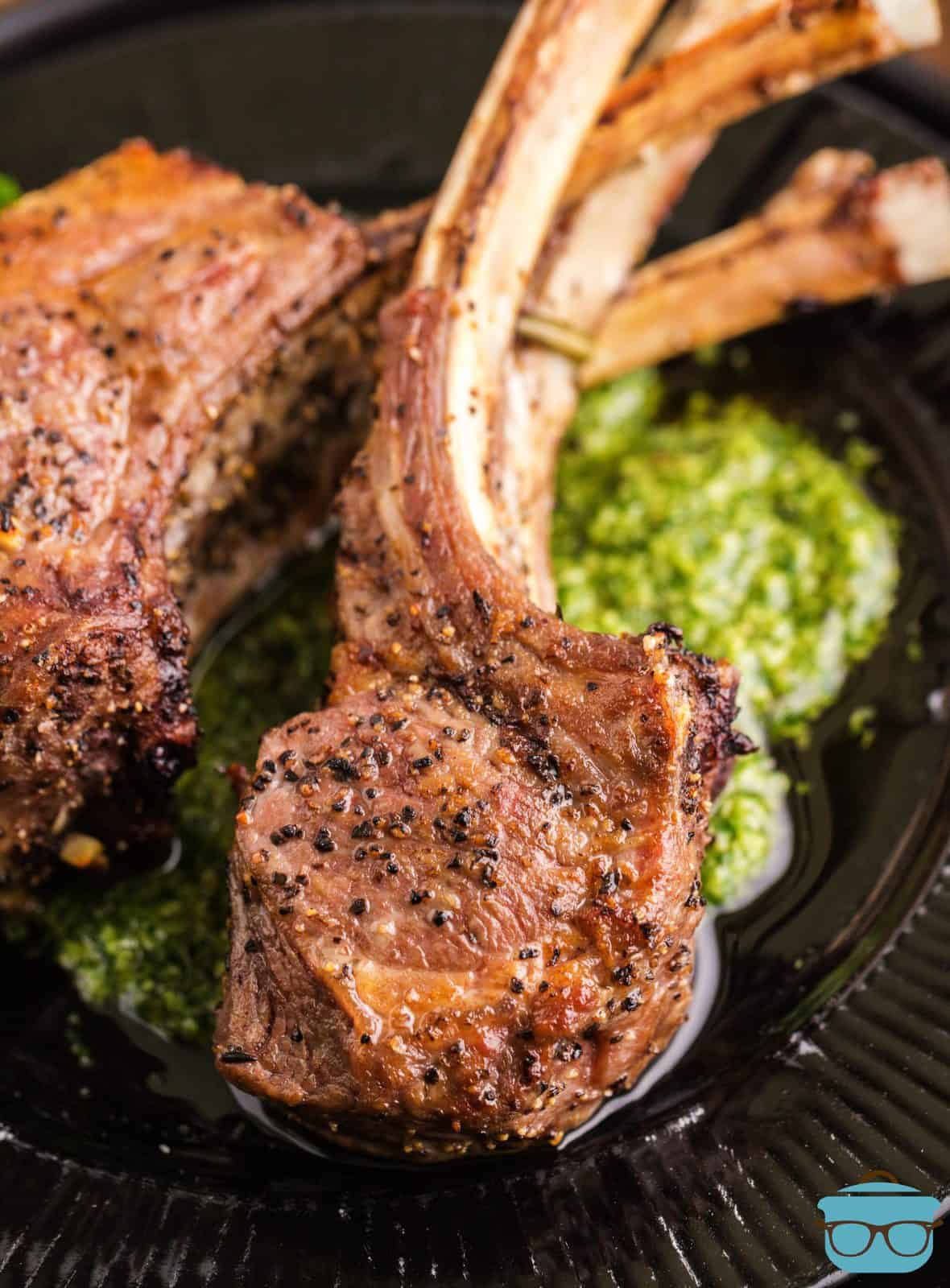 Plated Lamb Chops over Mint Pesto on black plate.