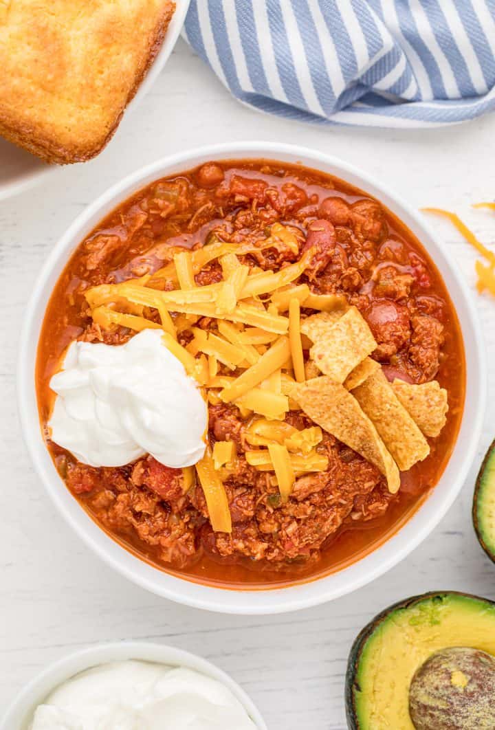 Overhead photo of bowl of Crock Pot Turkey Chili with cheese, chips and sour cream.
