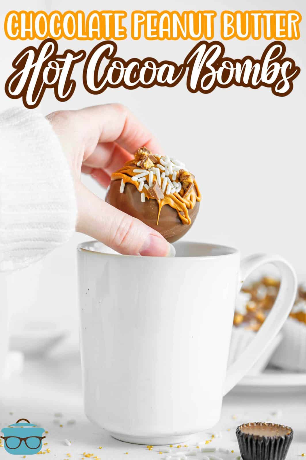 Pinterest image showing hand placing one Chocolate Peanut Butter Hot Cocoa Bombs into white mug.