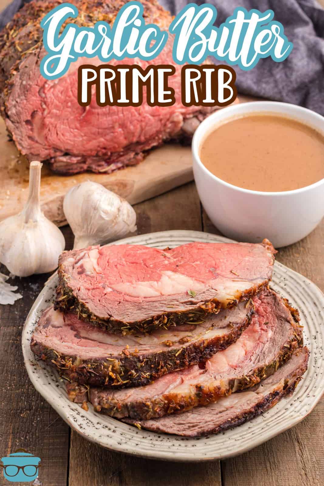 Pinterest image of sliiced Prime Rib on plate with garlic bulbs in background and au jus.