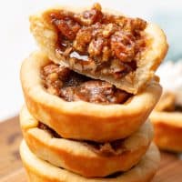 Square image of Pecan Tassies with one cut in half showing filling.