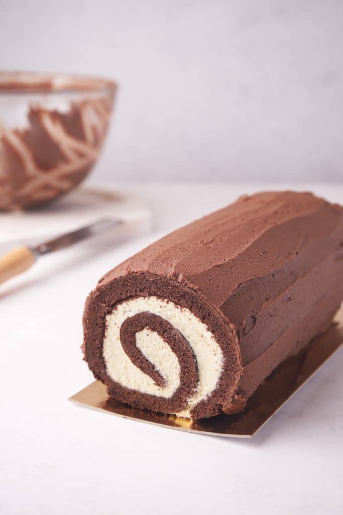 Rollled up cake spread with chocolate ganache.