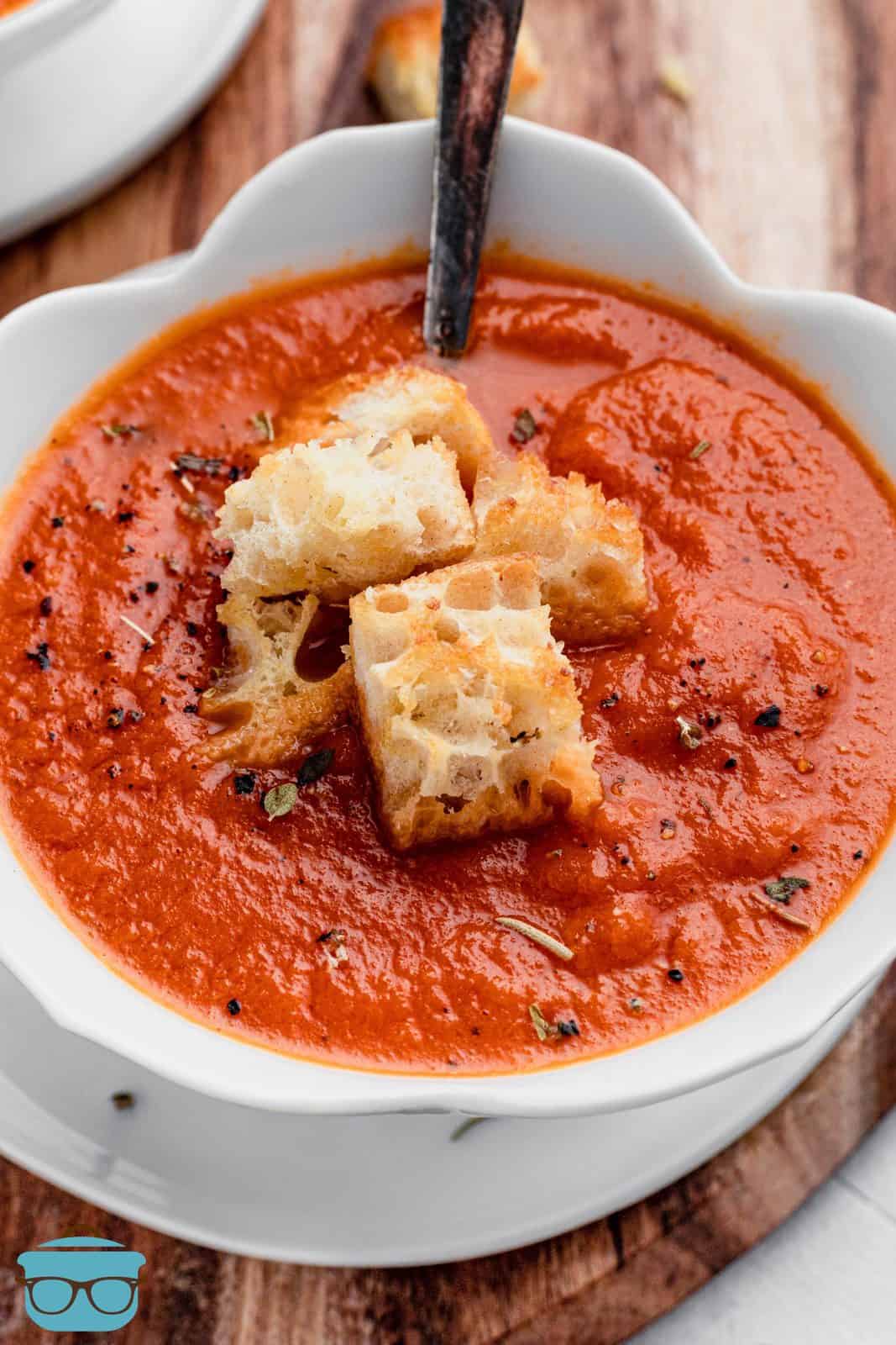 Easy Tomato Soup with Garlic Croutons close up in white scalloped bowl with spoon.
