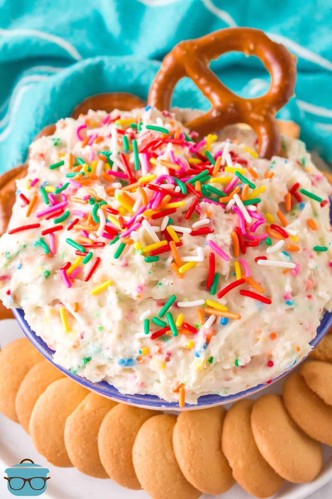 Funfetti Cake Batter Dip in bowl with pretzel in dip and cookies around bowl.