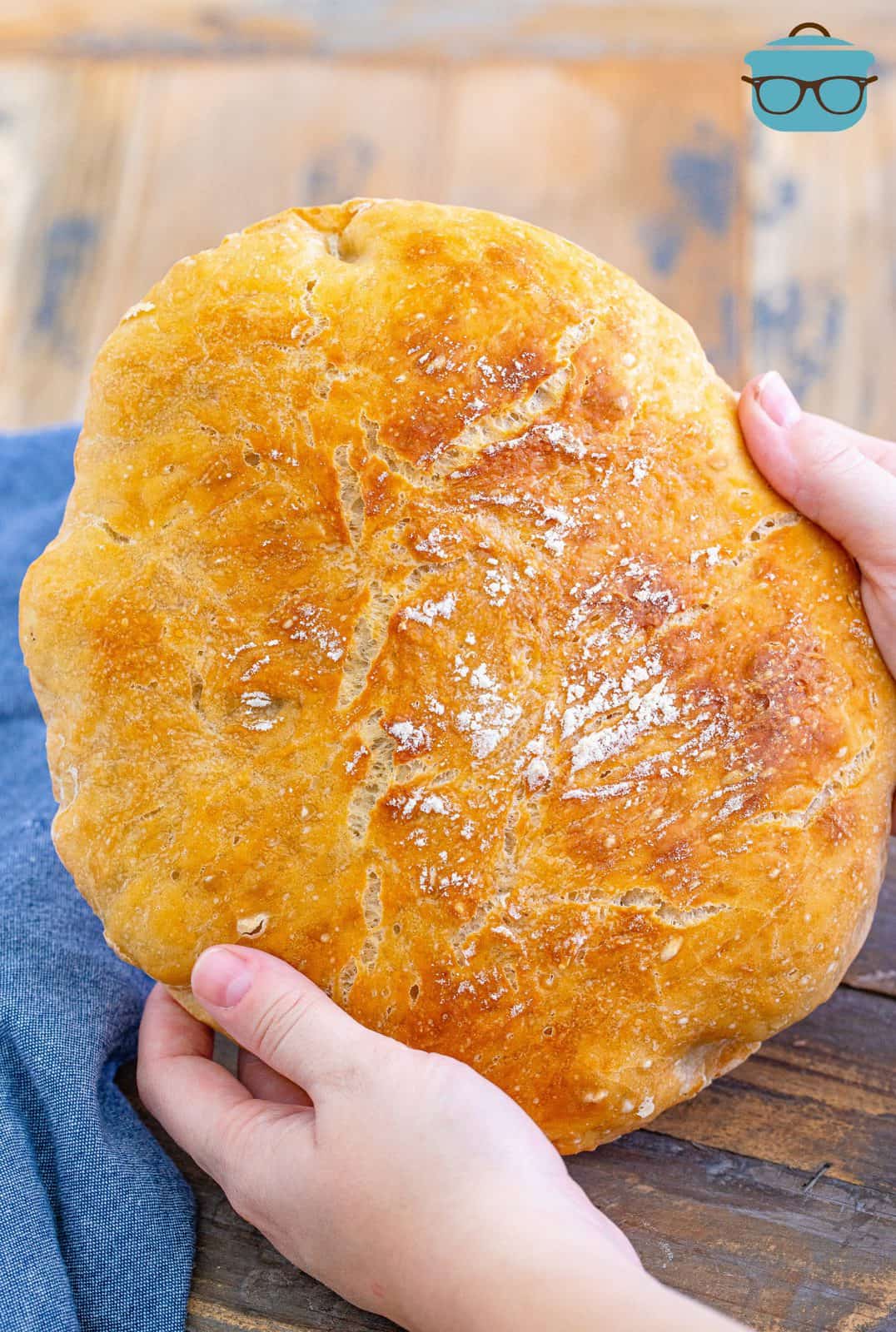 Hands holding No-Knead Dutch Oven Bread loaf.