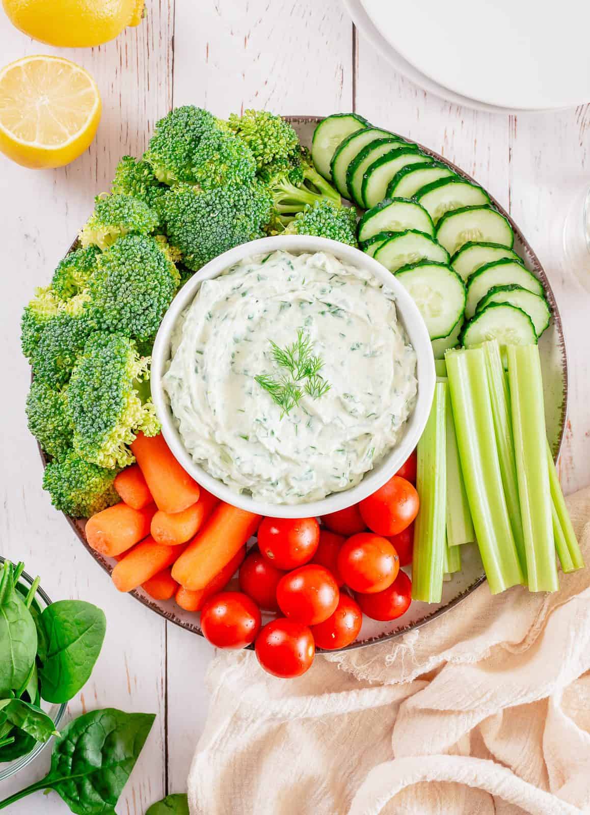 Overhead of Spinach Dip Recipe in bowl in the center of various vegetables, topped with dill.