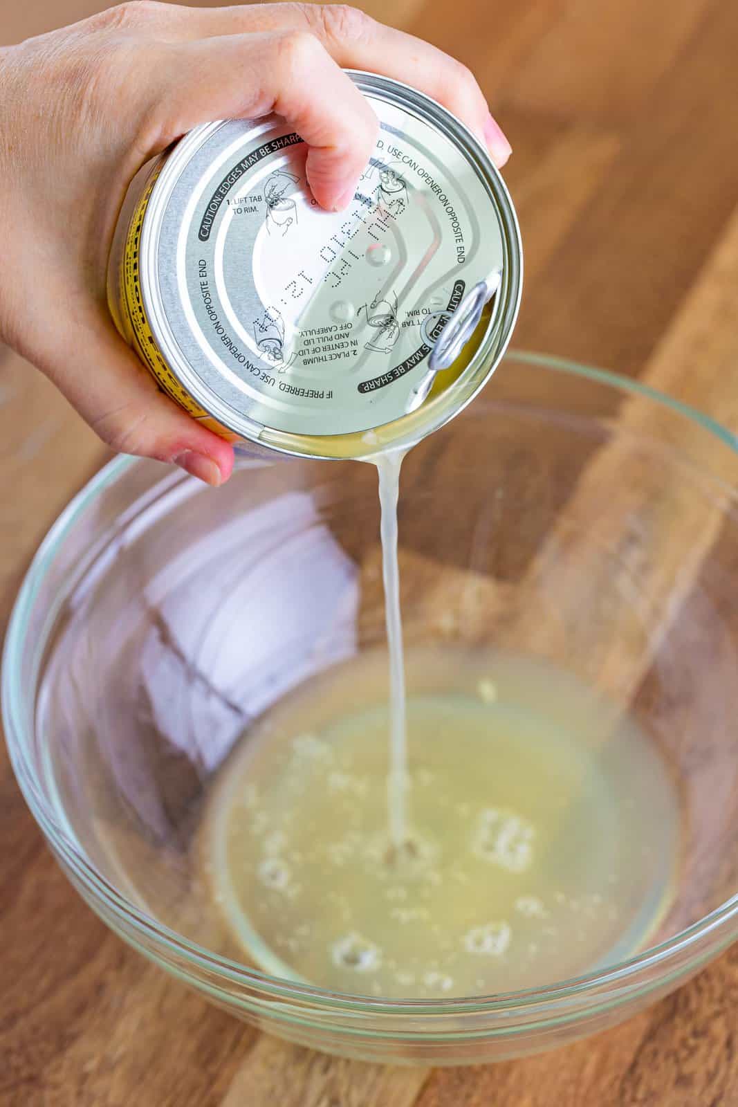 draining the pineapple juice from the can into a bowl. 