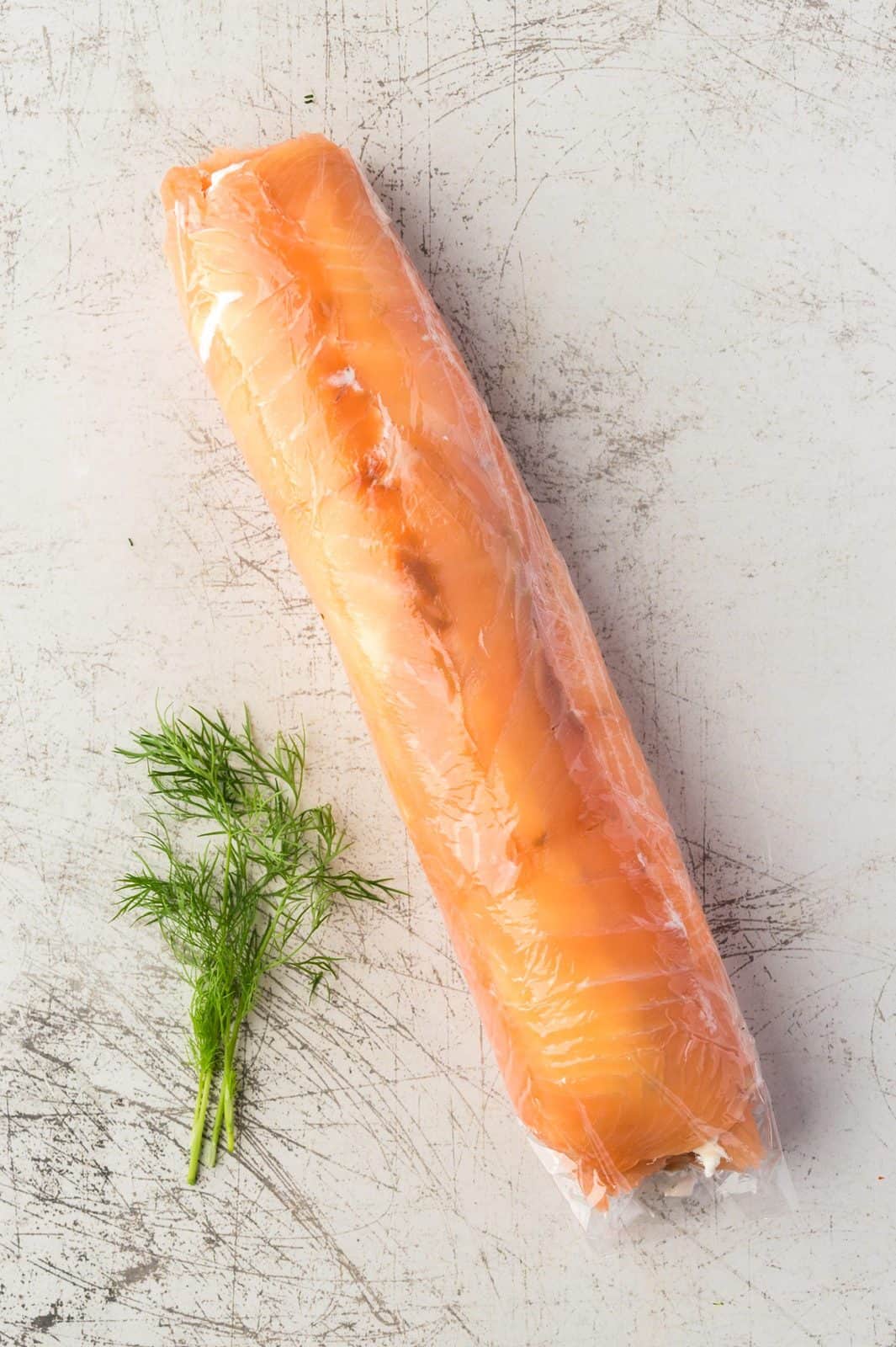 Rolled up salmon wrapped in plastic wrap.
