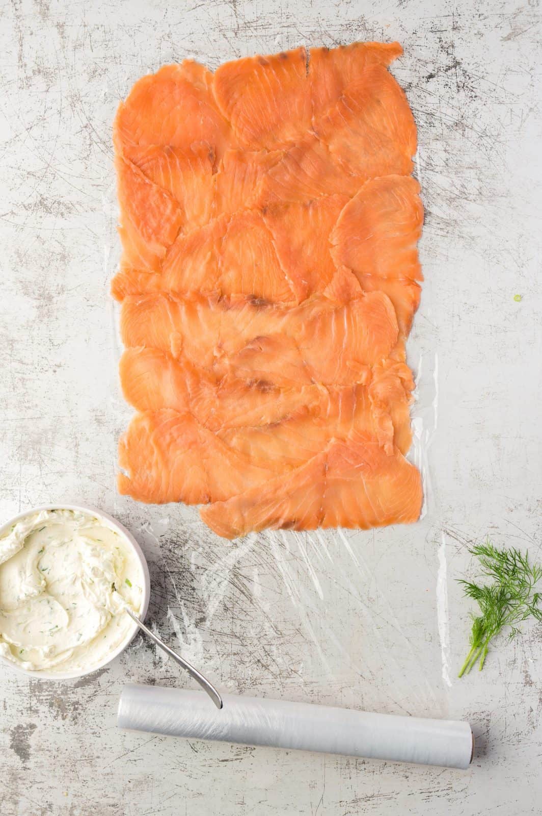 Salmon sliced layered, slightly overlapping on plastic wrap.