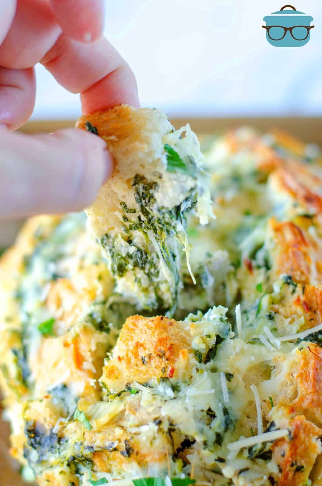 Hand pulling up some of the Spinach Artichoke Pull Apart-Bread.