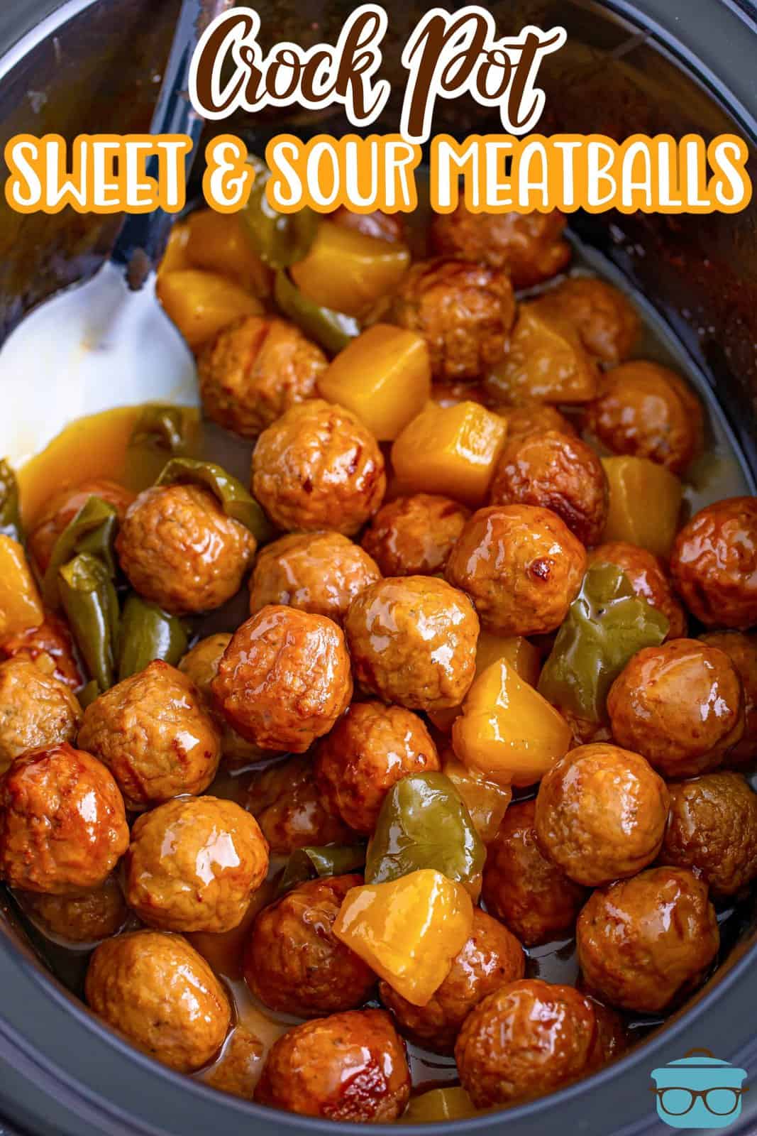 fully cooked sweet and sour meatballs in a black oval slow cooker with a silver spoon inserted into the meatballs. 