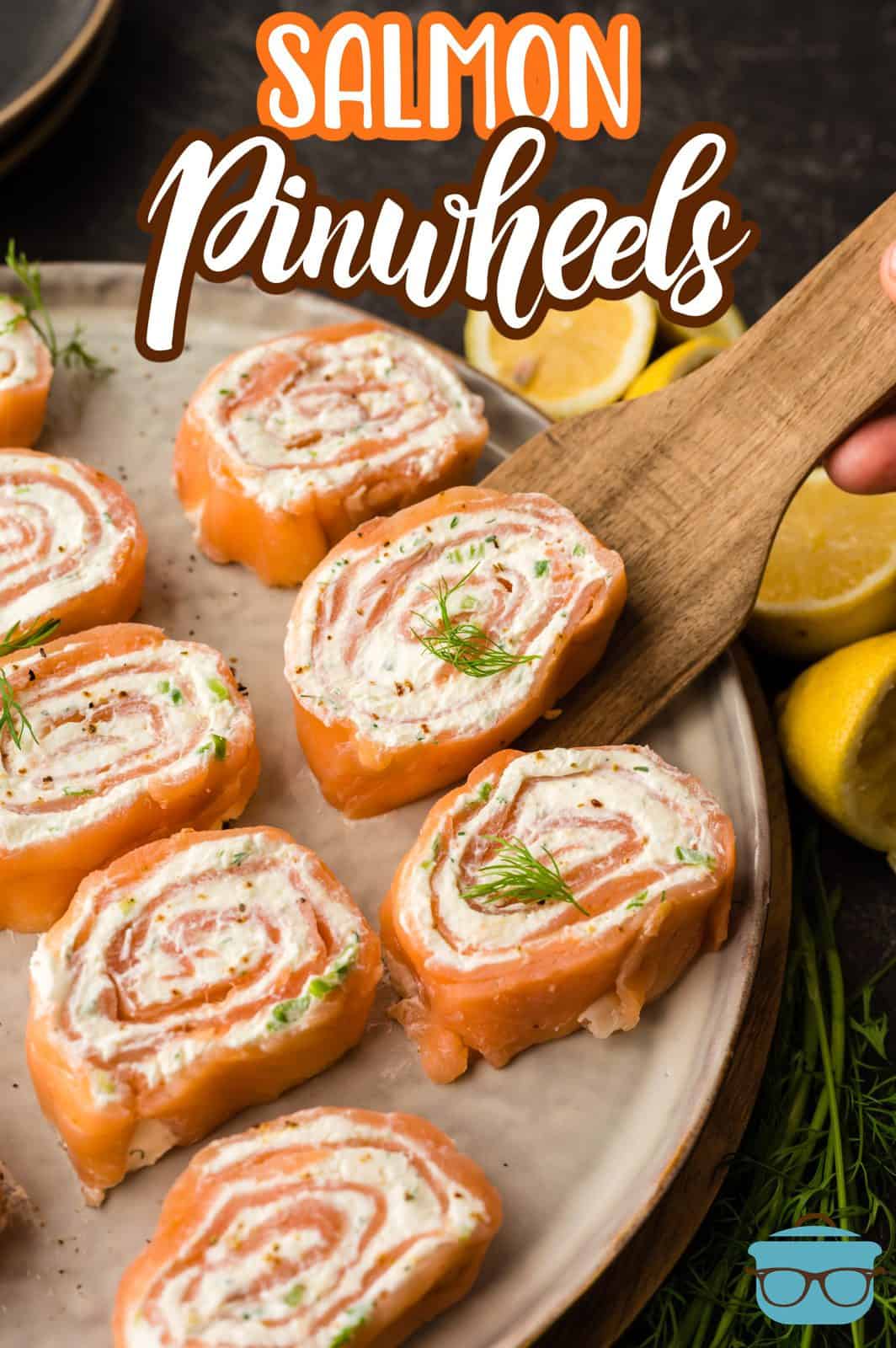 Pinterest image of Salmon Pinwheels sliced with one on a wooden spatula.