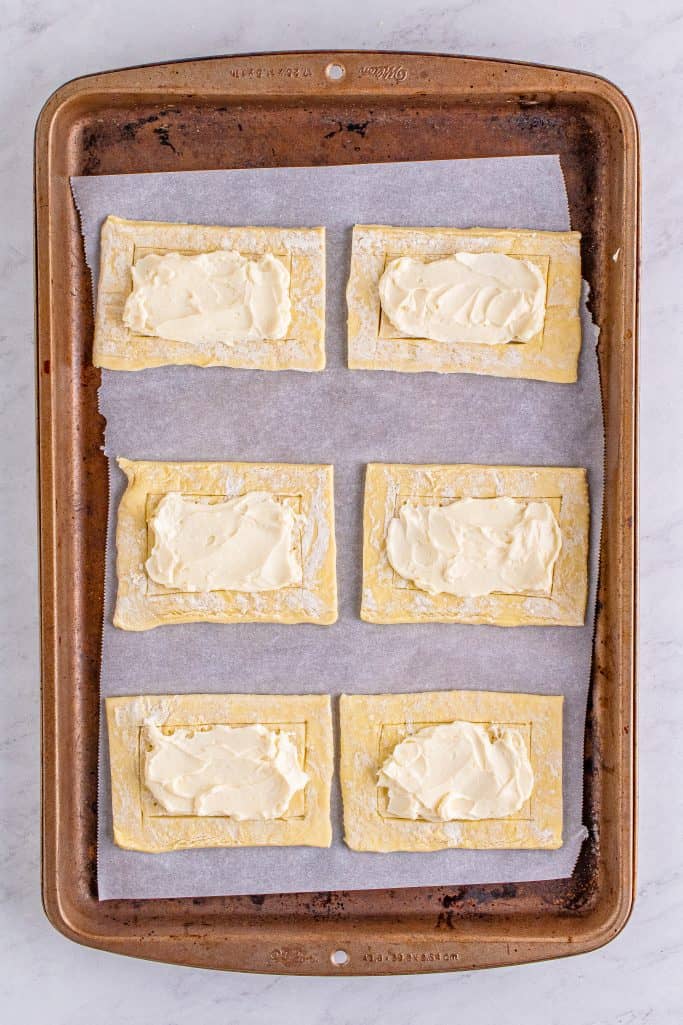 Cream cheese mixture spread in the middle of puff pastry pieces.