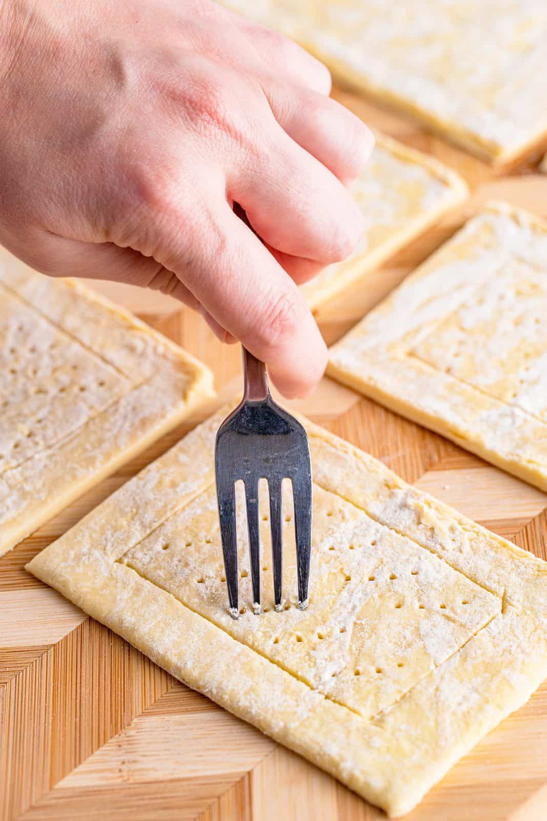 Fork poking holes in puff pastry.