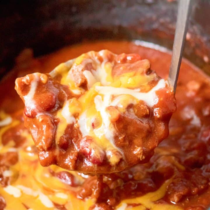 Square image with Slow Cooker Ultimate Beef Chili being held up with ladle.