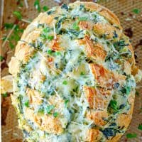 Square photo overhead of finished Spinach Artichoke Pull-Apart Bread on baking sheeet.