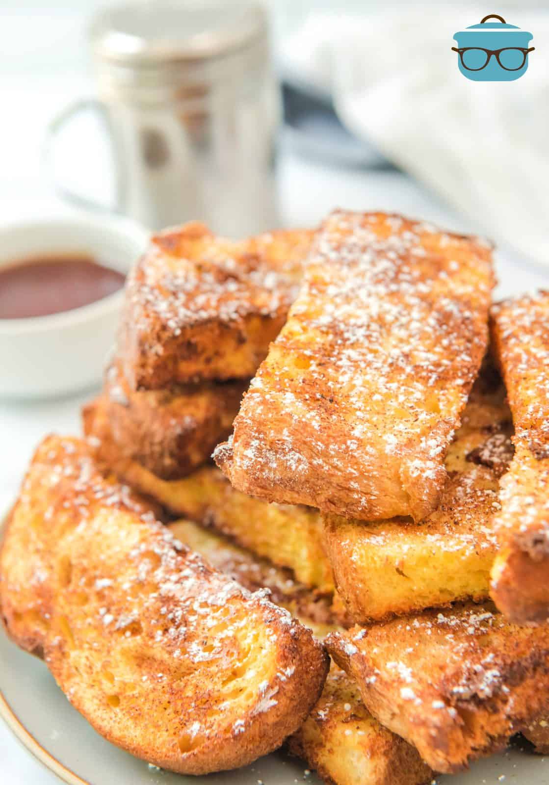 Stacked Air Fryer French Toast Sticks topped with powdered sugar.