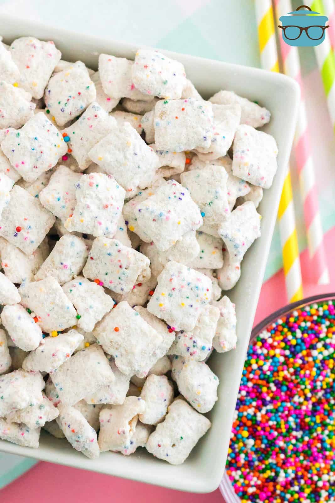 Overhead of Funfetti Puppy Chow in bowl with sprinkles next to bowl.