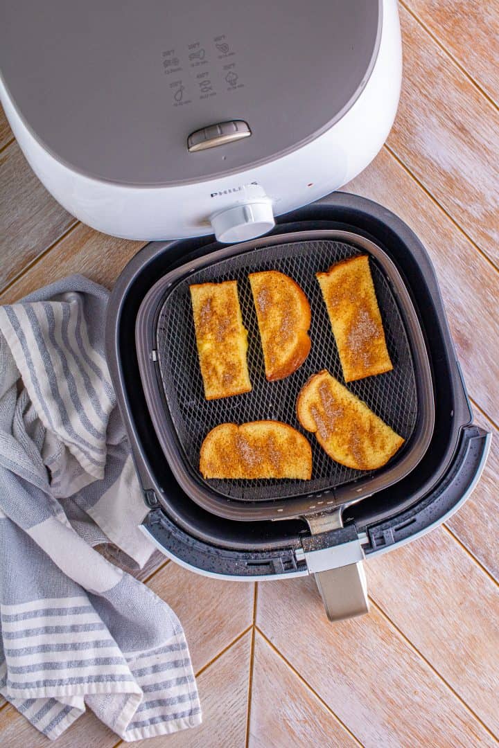 uncooked French toast slices shown in the basket of an air fryer.