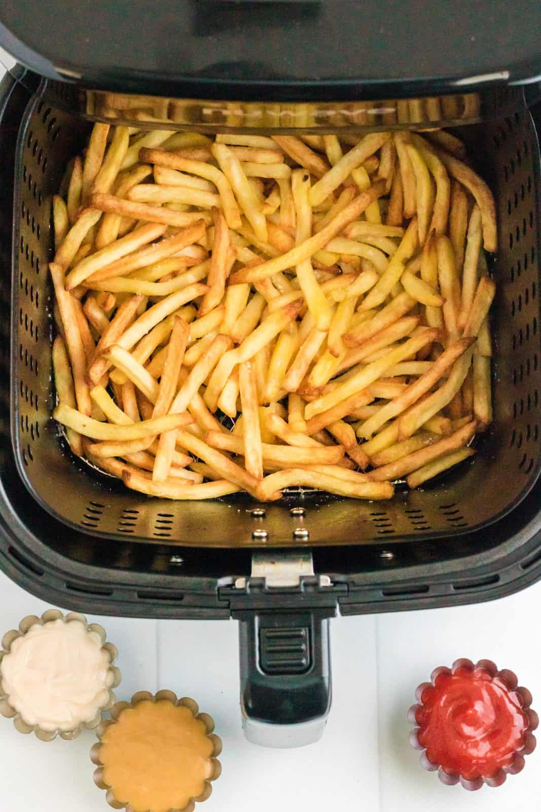 Crispy finished french fries in air fryer basket.