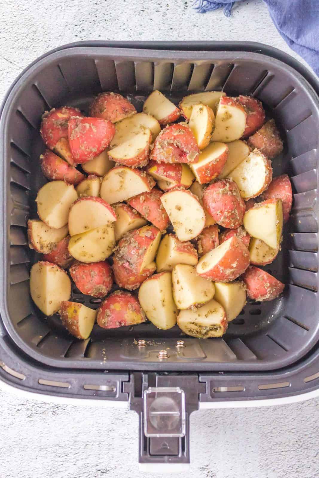 Coated potatoes added to air fryer basket.