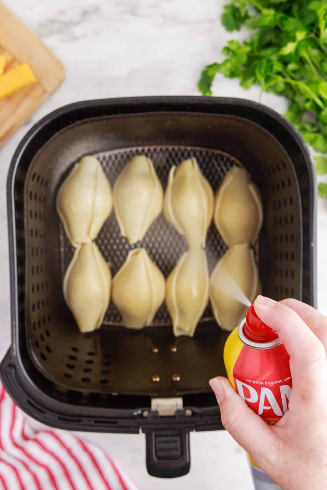 Stuffed Shells being sprayed with non-stick cooking spray.