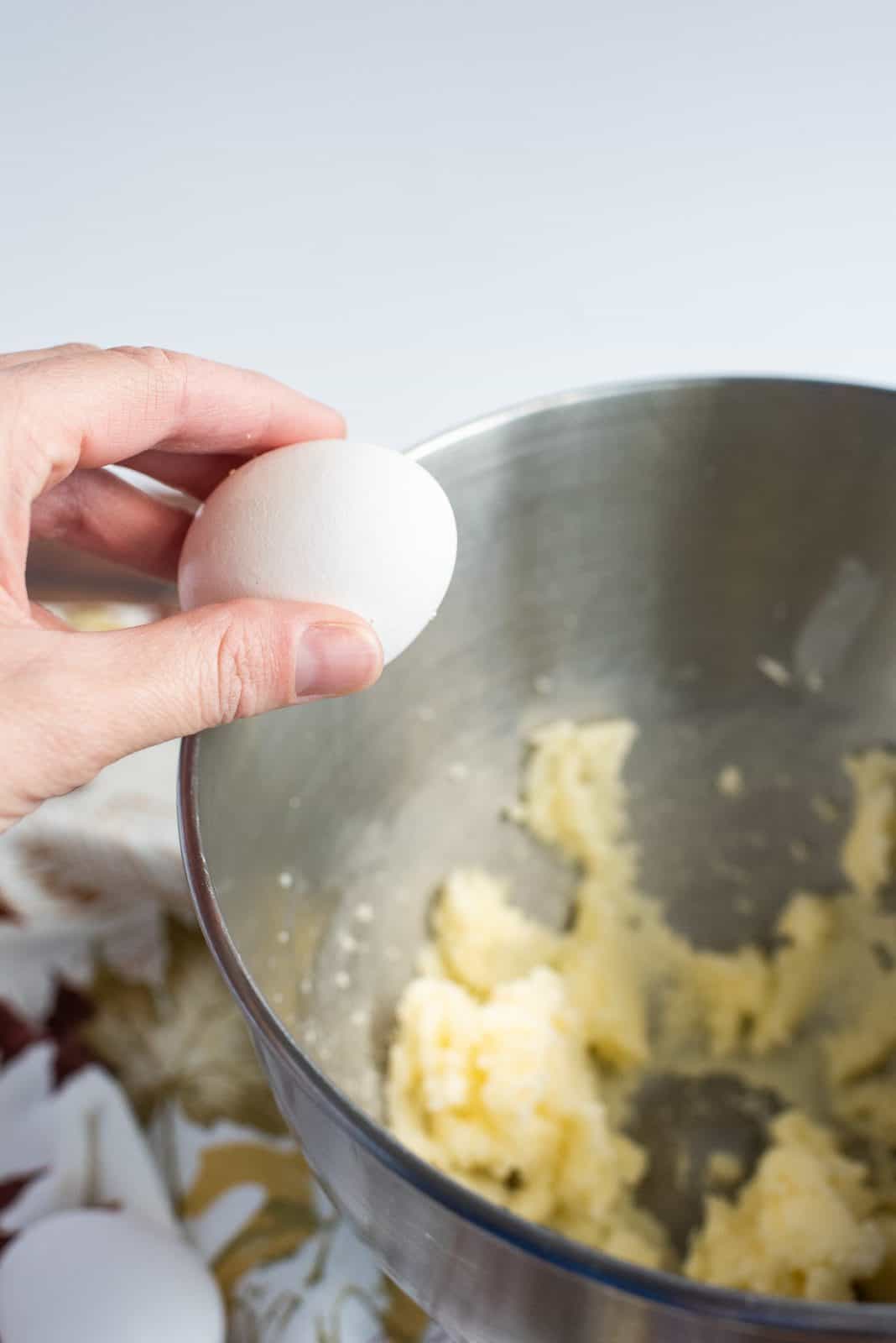 Egg being added to bowl of stand mixer.