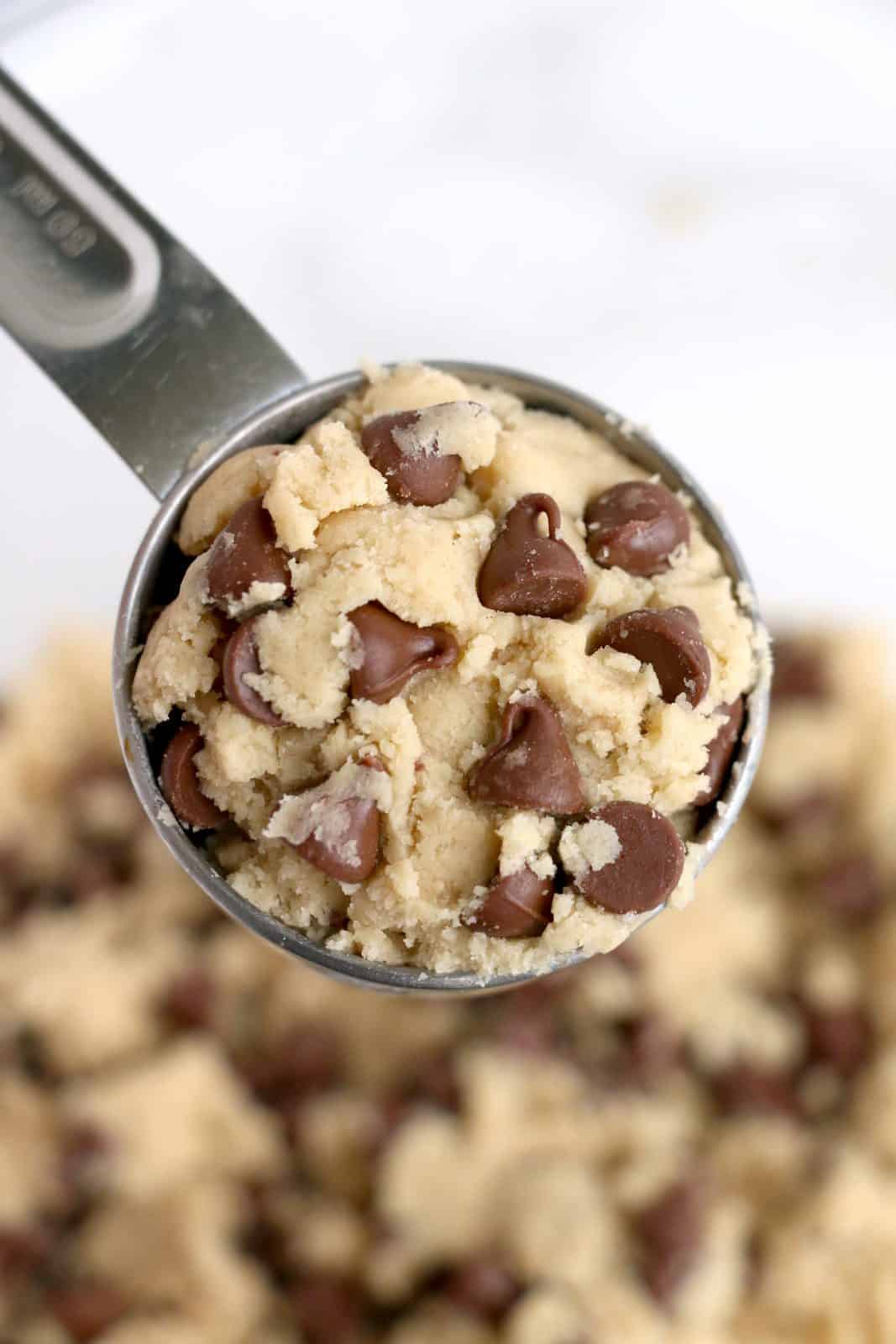 Cookie dough scooped into a ¼ cup measuring cup.