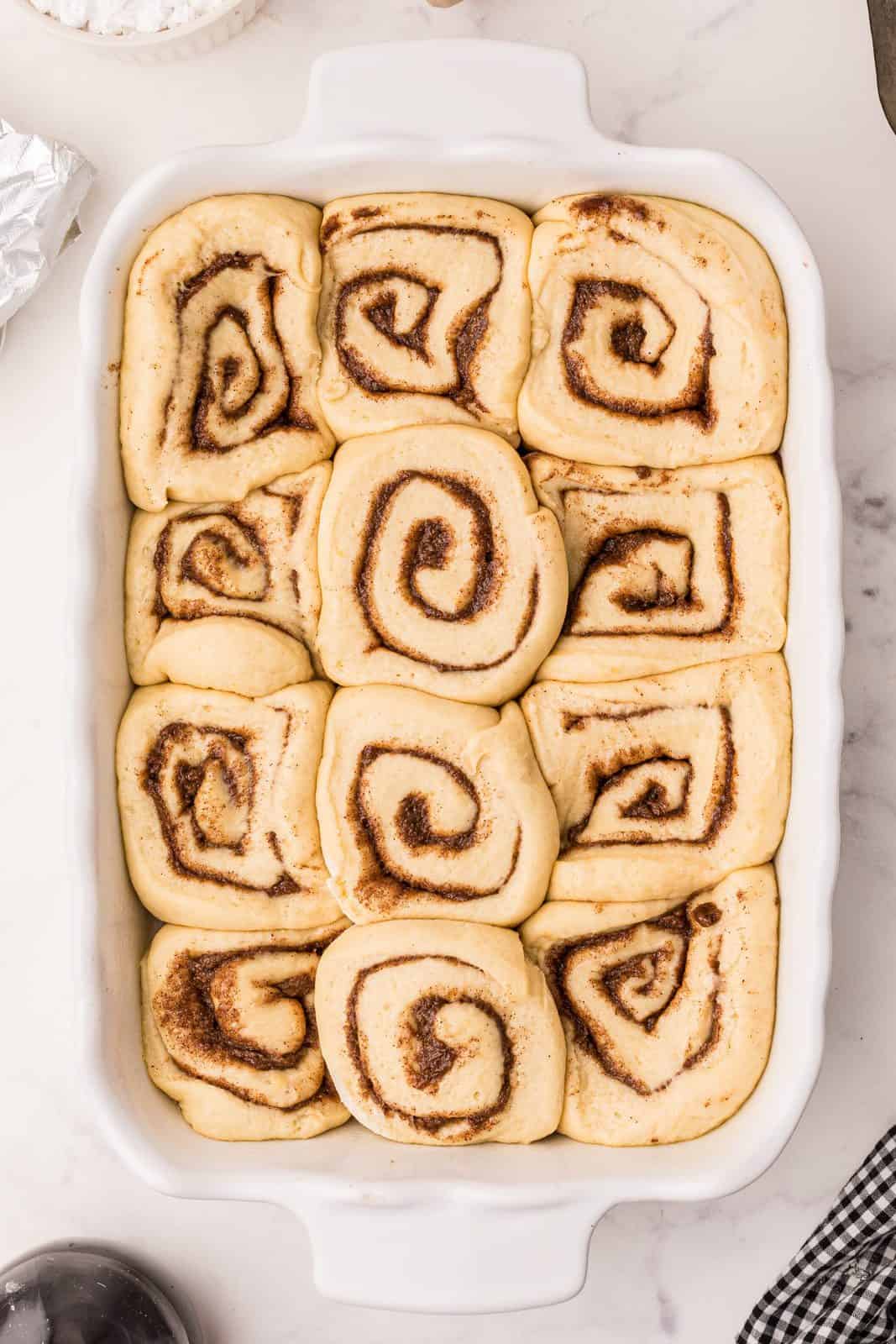 Risen cinnamon rolls in baking pan.