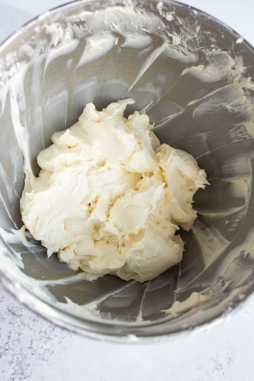 Sugar and cream cheese beated together in bowl of stand mixer.