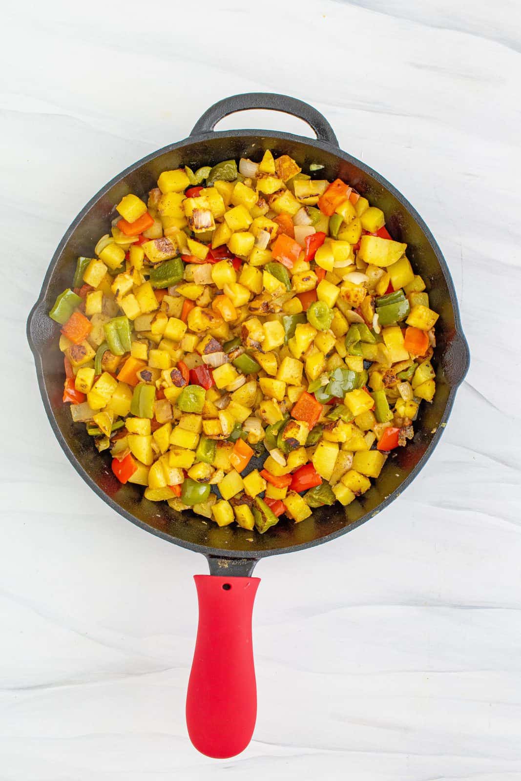 Cooked potatoes in vegetables in skillet.