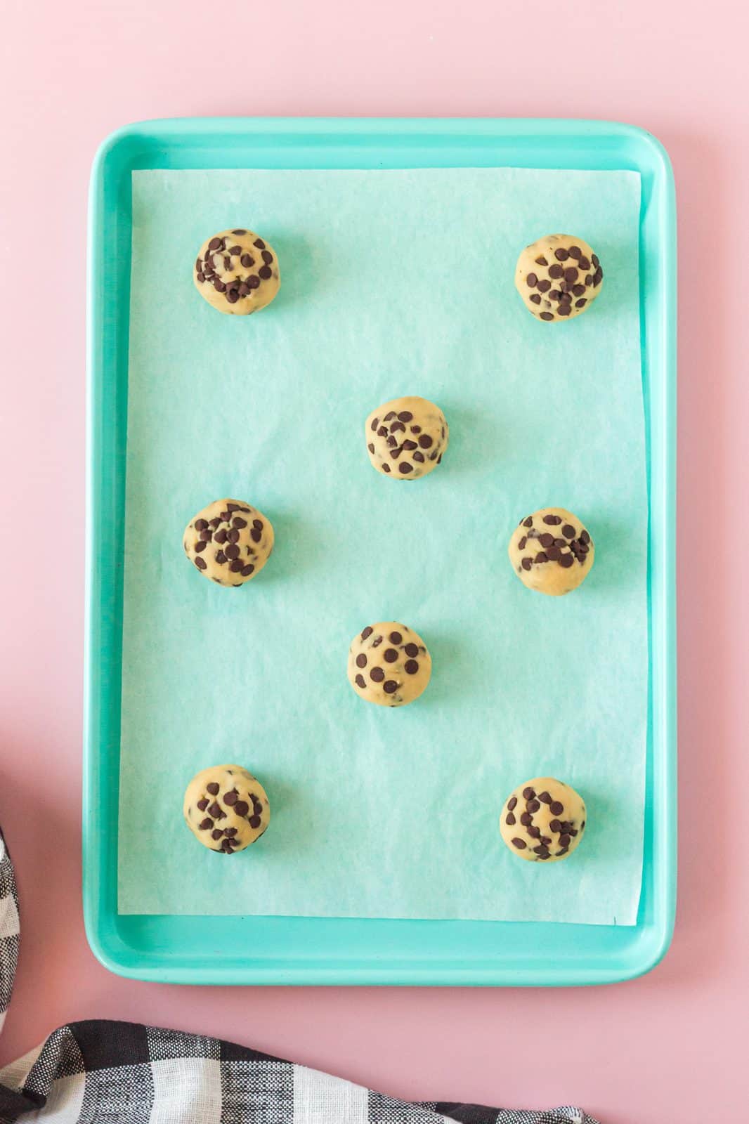 Cookie dough ablls on parchment lined baking sheet.