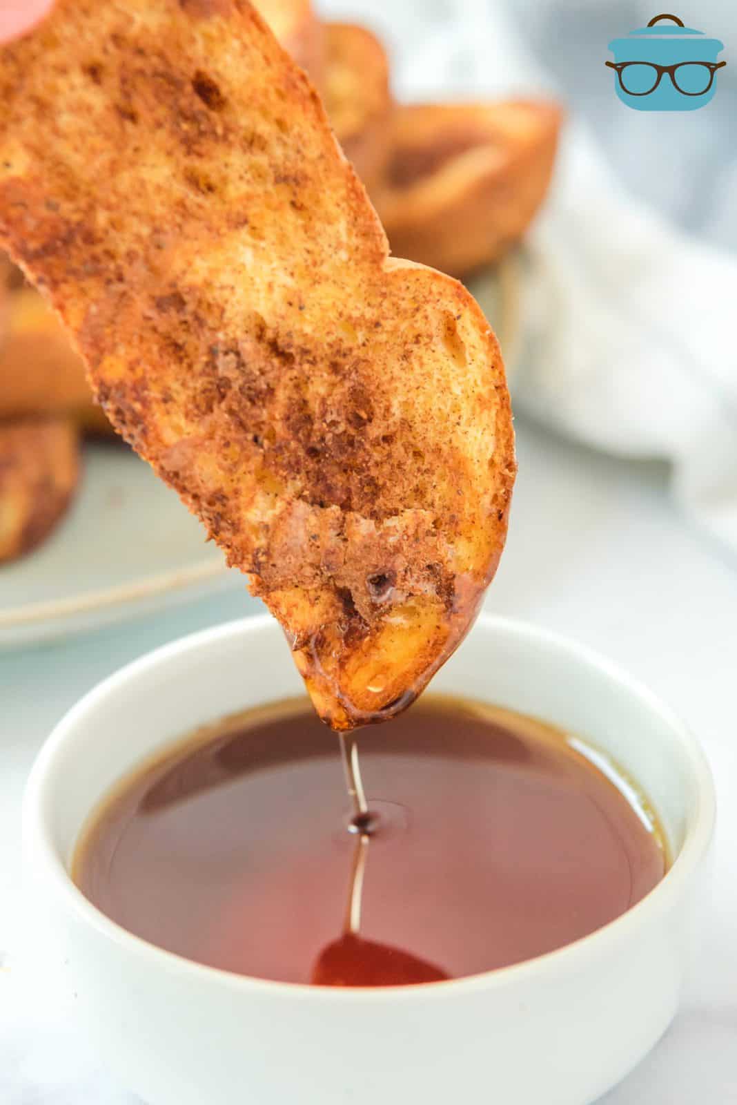 Hand dipping one Air Fryer French Toast Stick into syrup.