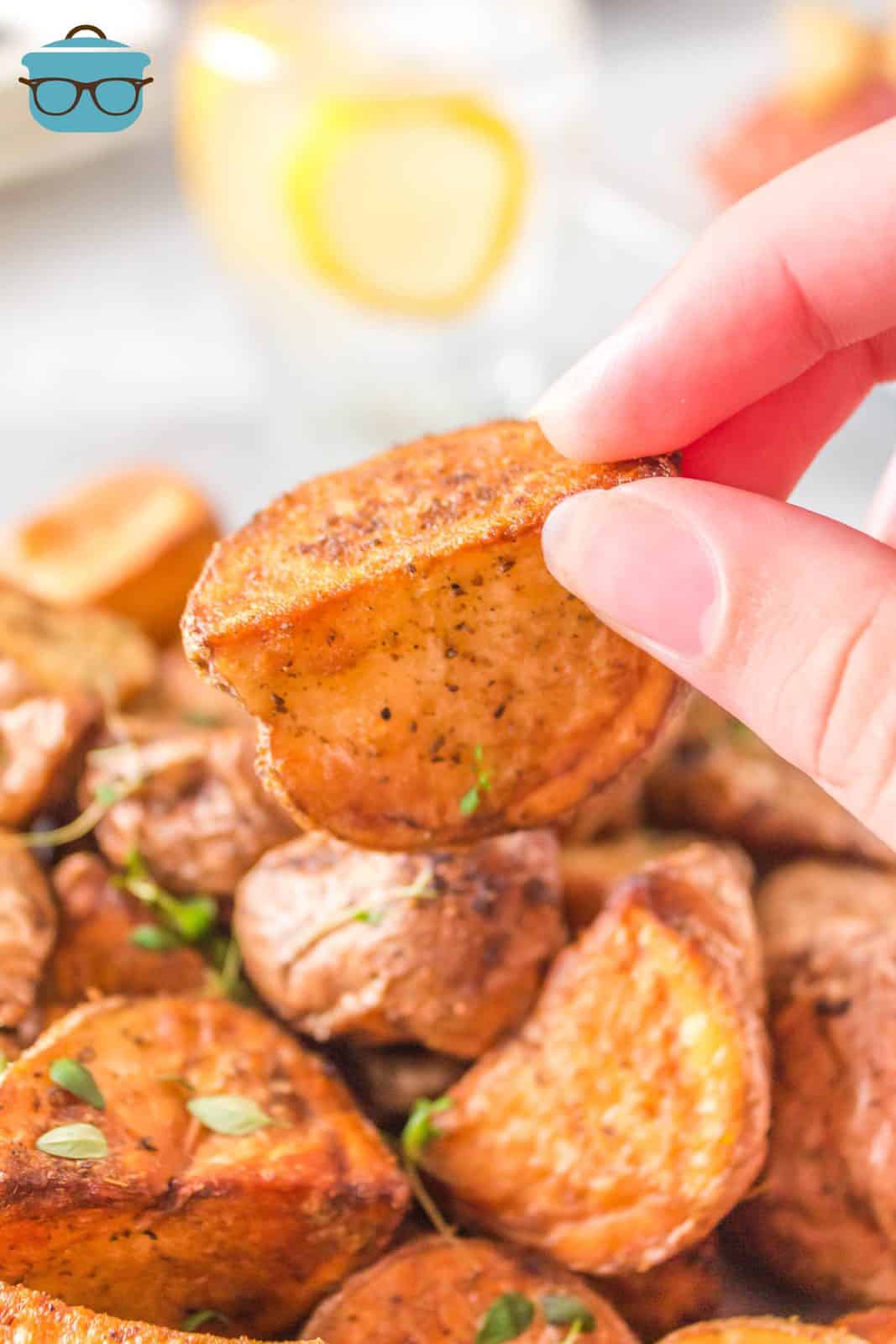 Hand holding up one Air Fryer Roasted Red Potato.