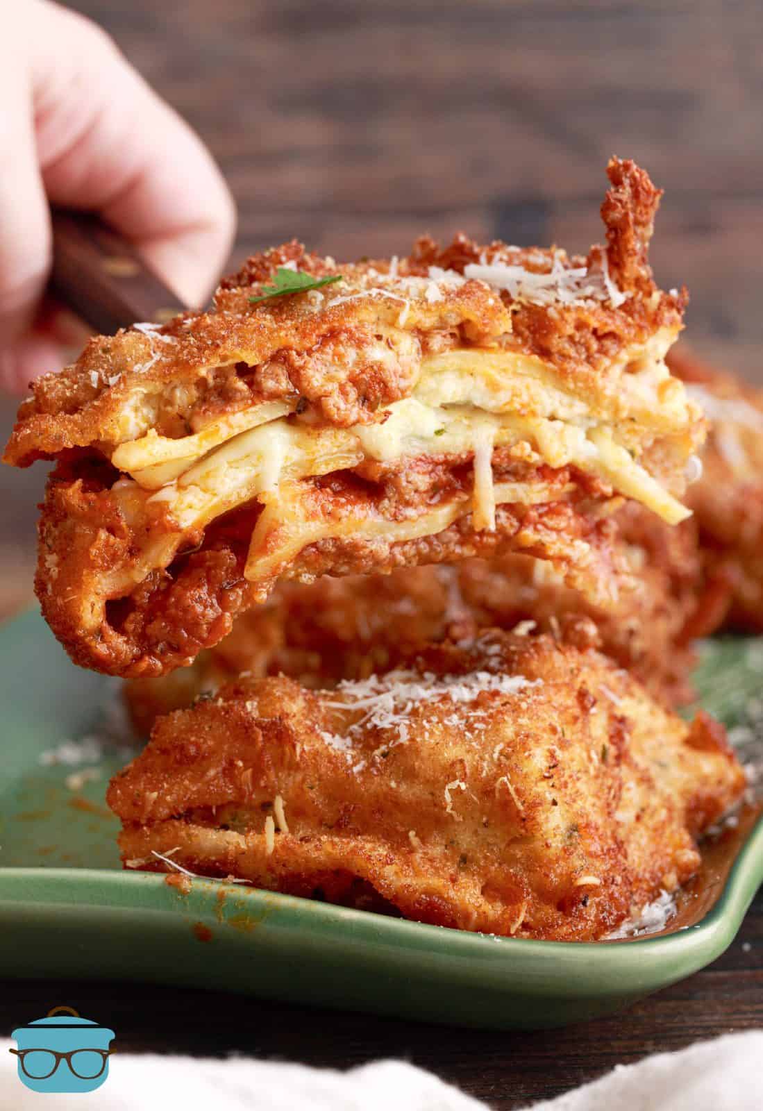 Spatula holding up a piece of Deep Fried Lasagna split in half showing middle.