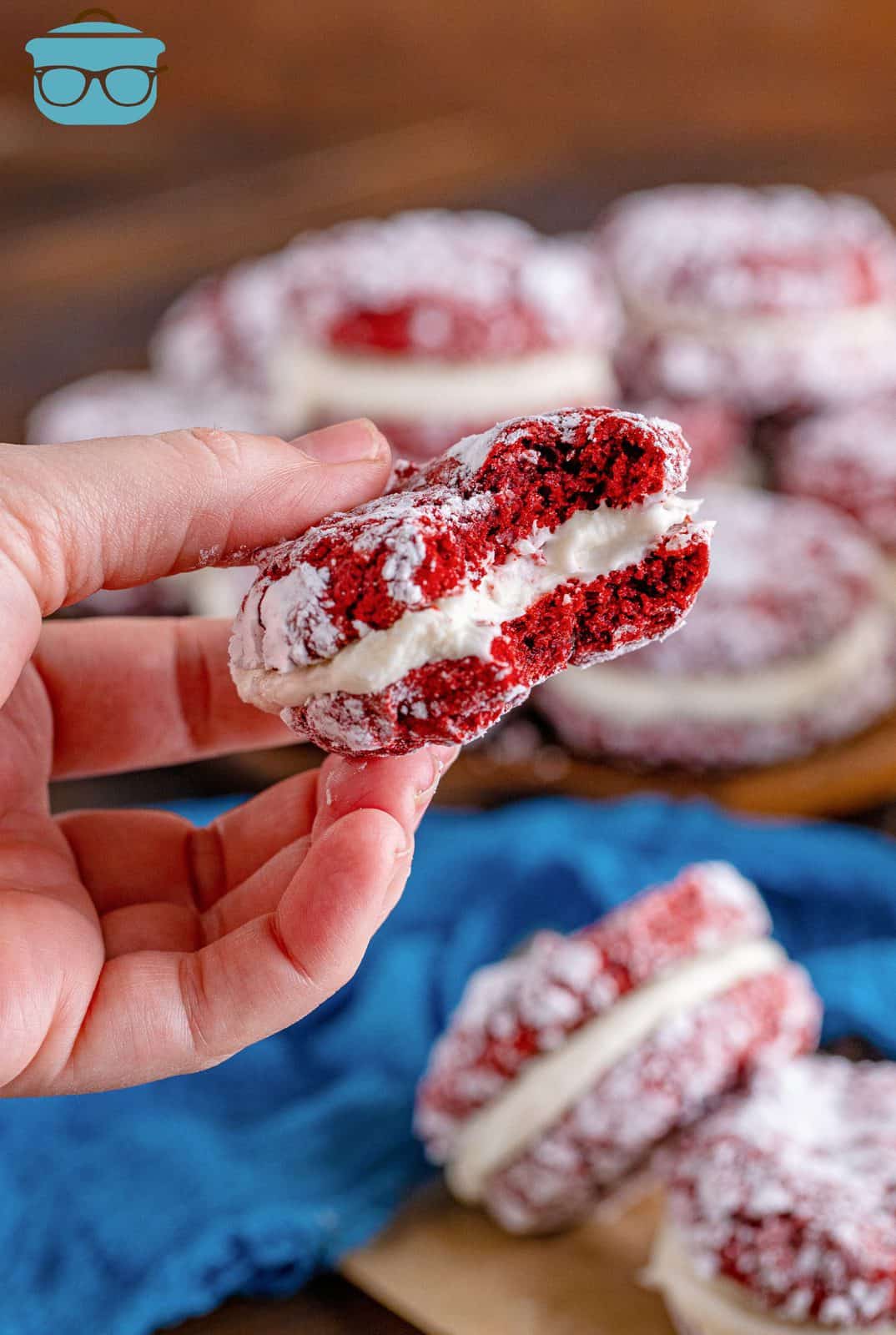 Hand holding one Red Velvet Sandwich Cookie with bite taken out of it.