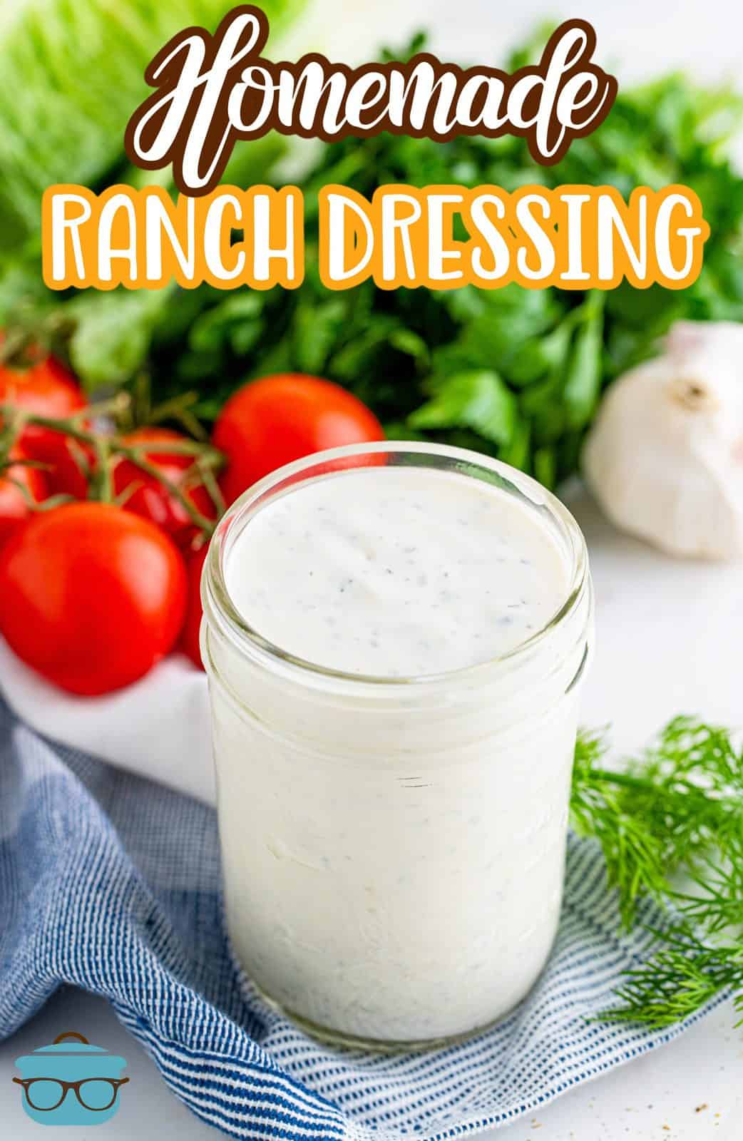 homemade ranch dressing shown in a small mason jar with fresh tomatoes and lettuce in the background.