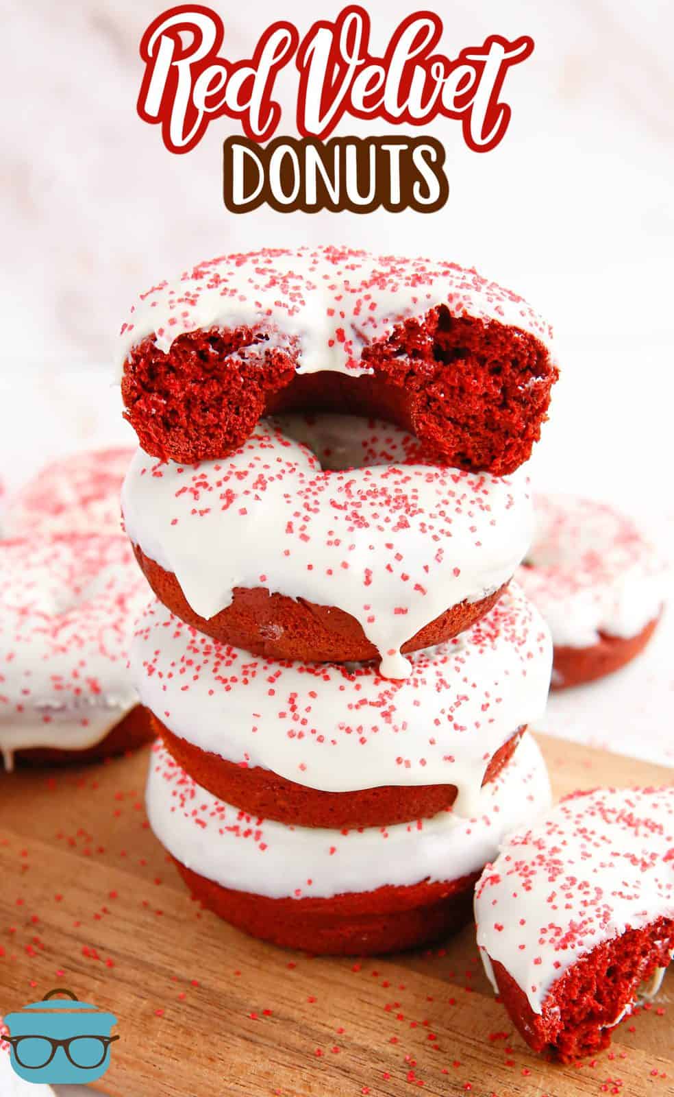 Four stacked Baked Red Velvet Donuts on cutting board with top donut broken in half.