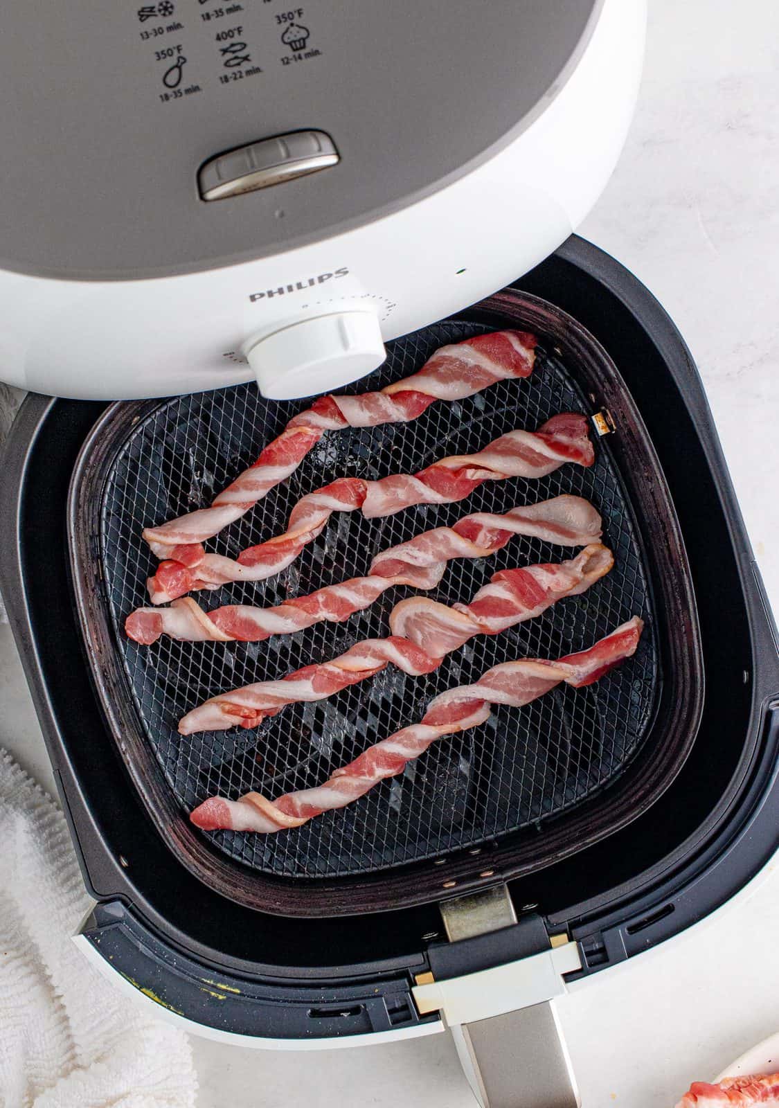 Bacon twisted in basket of air fryer.