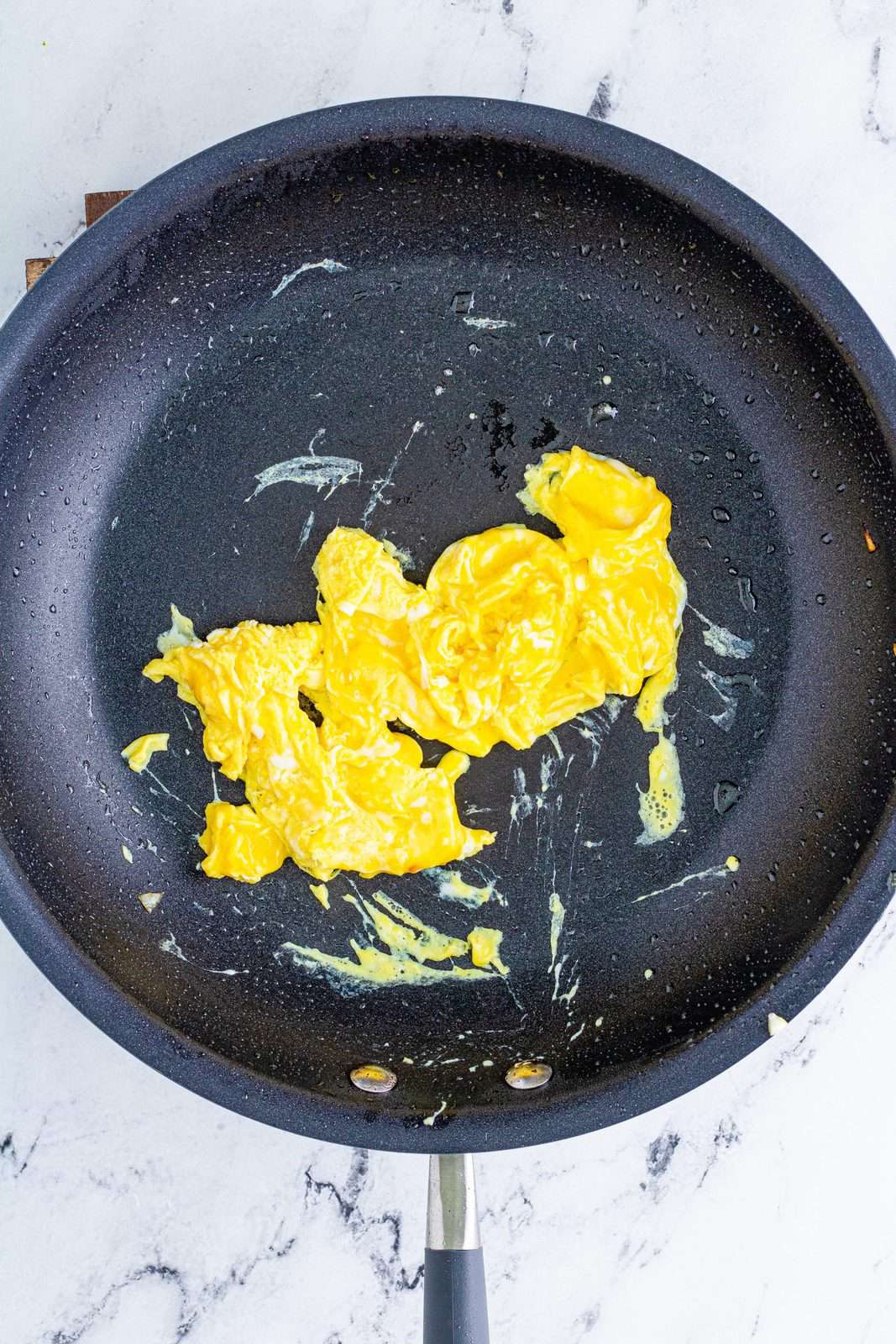 Eggs being scrambled in pan.