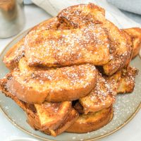 Square image of Air Fryer French Toast Sticks stacked on plate.