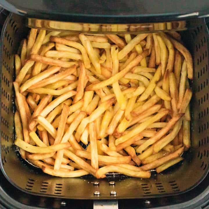 Square image of finished french fries in air fryer.