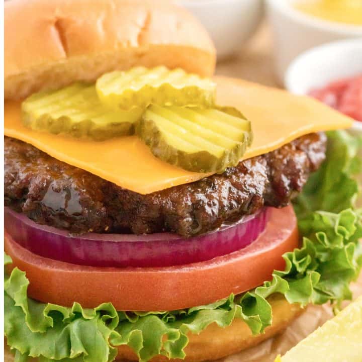 Square image close up of Air Fryer Hamburgers with toppings and bun off to the side.